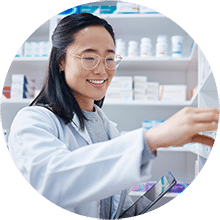 A pharmacist organizing medication bottles on a shelf in the pharmacy