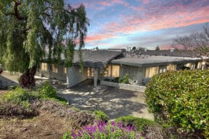 The front entrance of All Saints surrounded by trees and flowers