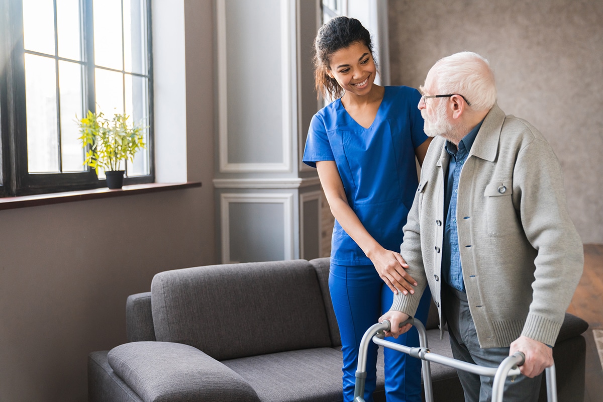 Portrait of a young nurse helping man to walk using walker equipment