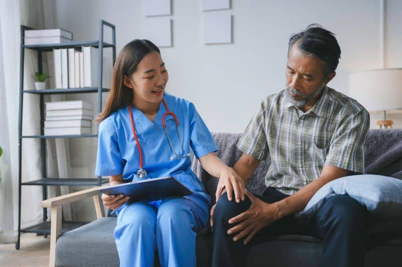 Nurse checking painful knee of patient