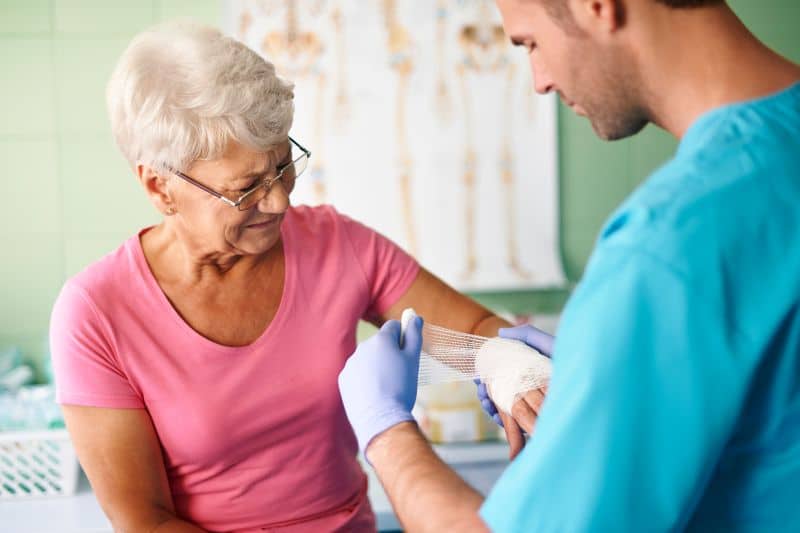Nurse wrapping wounded hand of patient