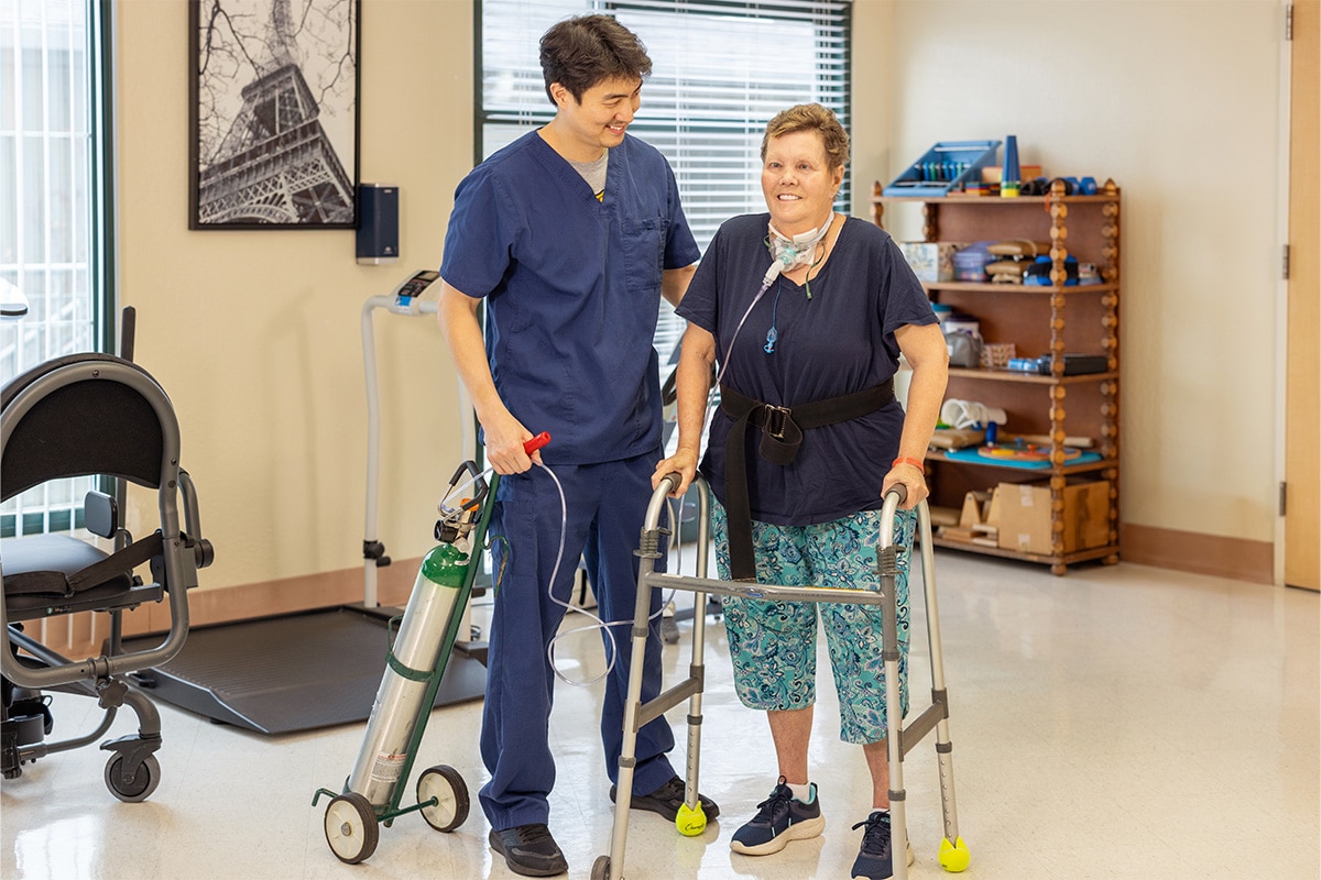 All Saints Post Healthcare nurse with resident standing in a walker