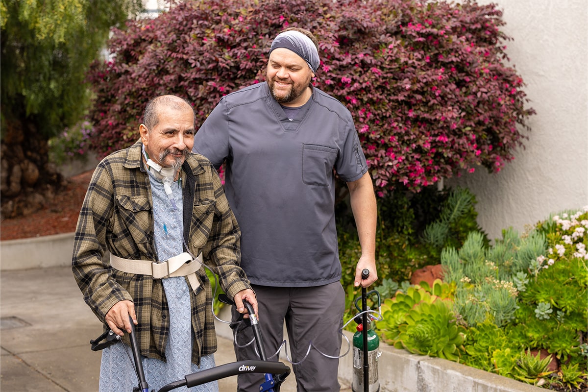All Saints Post Healthcare male nurse walking with resident